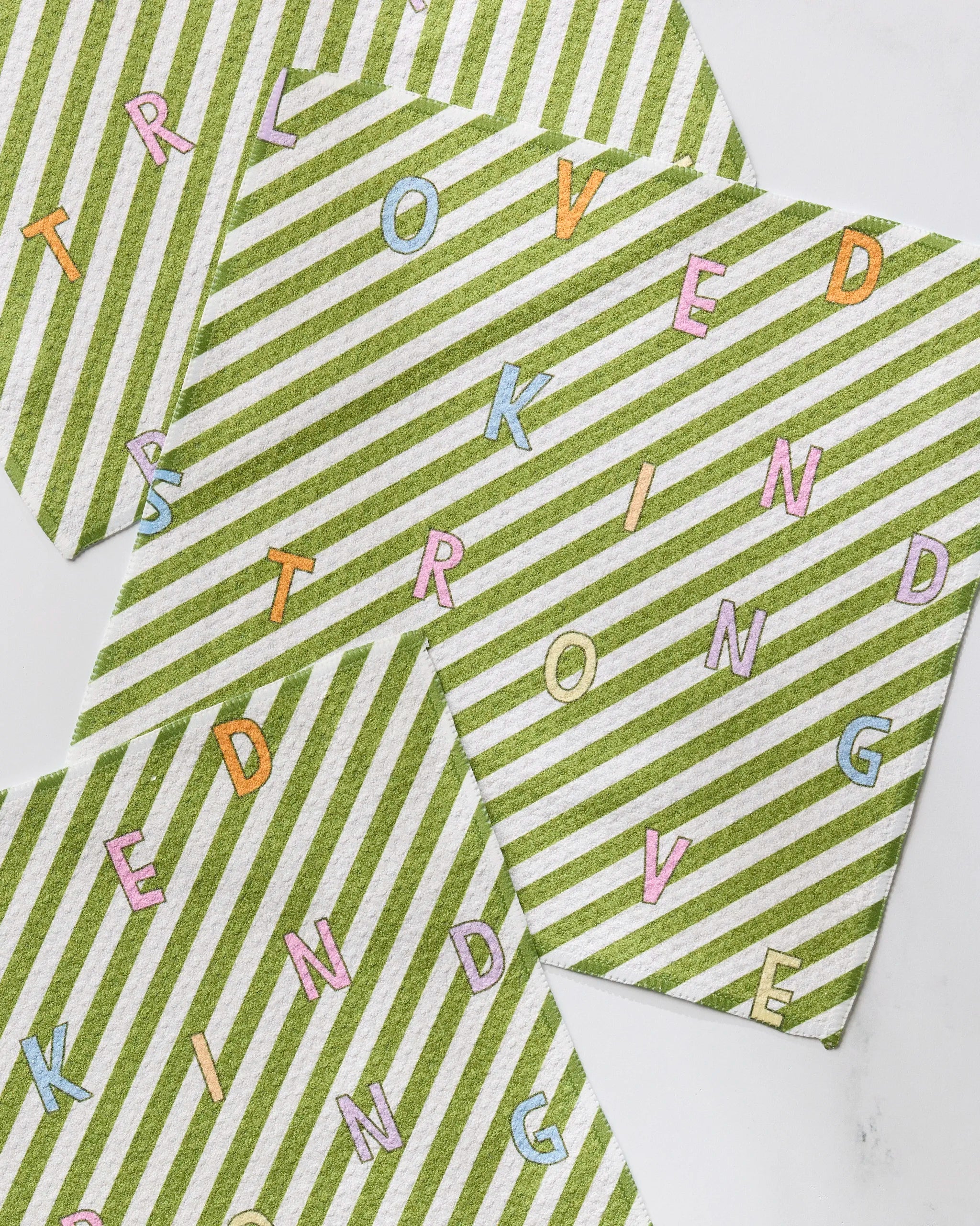 Geometry’s Attributes napkins come in a set of three green and white stripes, made from recycled materials, and showcase vibrant letters spelling LOVED, KIND, STRONG, and LOVE.