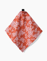 Ashley Celena’s “Autumnal Reverie” is a red cloth napkin with a white floral pattern, made from recycled materials, shown hanging by a black loop against a plain white background.