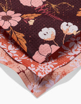 The Autumnal Reverie dishcloth set by Ashley Celena includes three recycled-fabric layers: a dark floral top, a rusty red middle with pink blooms, and a light pink bottom—each featuring unique floral patterns.