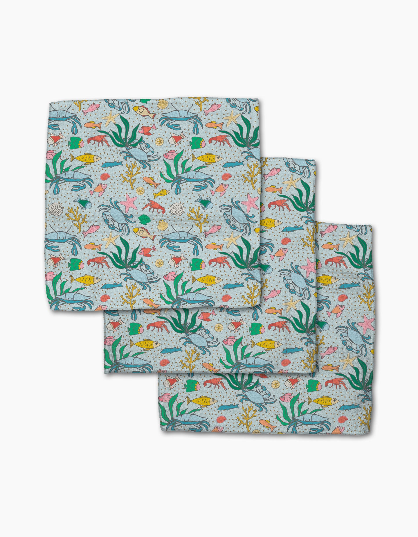 The Mindfulnice Beneath the Waves set includes three colorful napkins made from recycled materials, featuring fish, seaweed, coral, and starfish patterns on a light background.