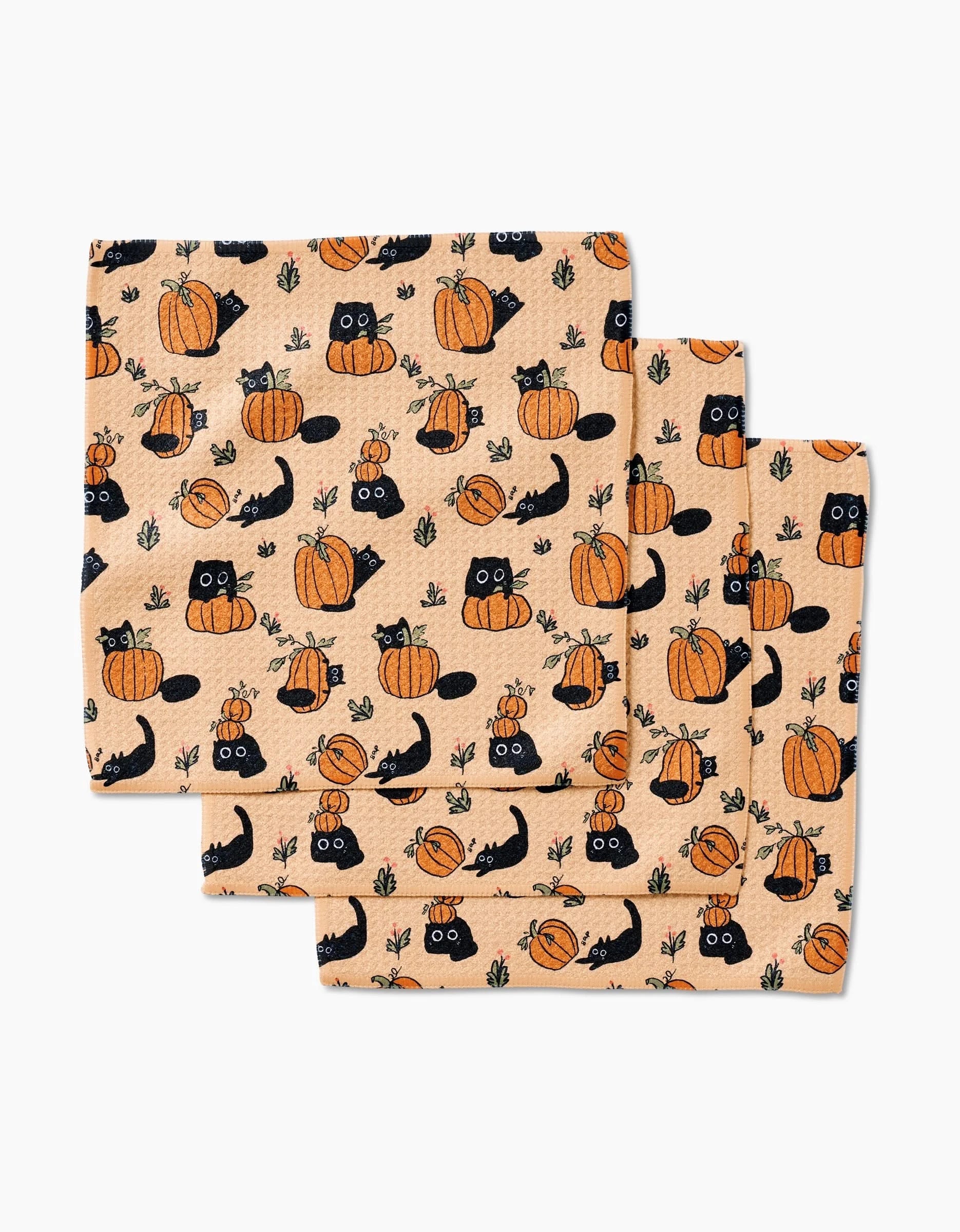 The Black Cats napkins by Janna Sue Design are a set of three, made from recycled materials, with black cats, pumpkins, and green leaves on a light orange background for a festive autumn look.