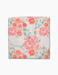 The Blush Florals dishcloth by Elena Fay features white Geoweave fabric with a textured pattern, adorned with vibrant pink and orange watercolor florals and green leaves.
