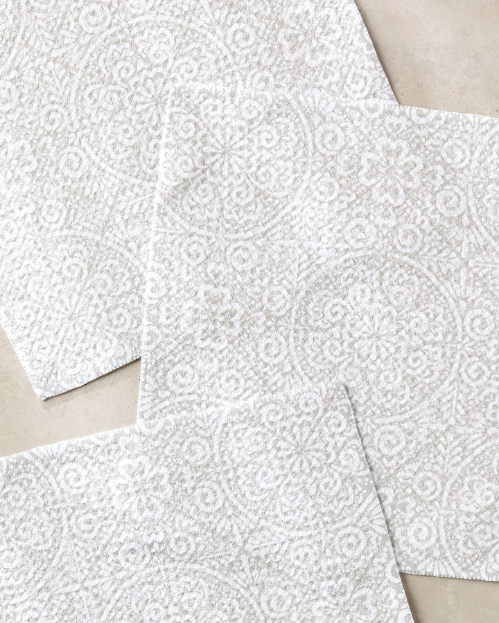 Three Boho Medallion tiles by Kris Ruff—white with intricate floral and circular textures, made from recycled materials—are overlapped on a light beige surface in a layered arrangement.
