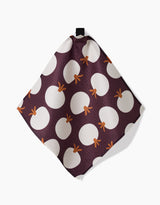 The Bold Fall dish towel by Lizzie Clark features a dark purple background with large white circles and orange stems like stylized pumpkins. Fast-drying and square, it includes a small black hanging loop at the top.