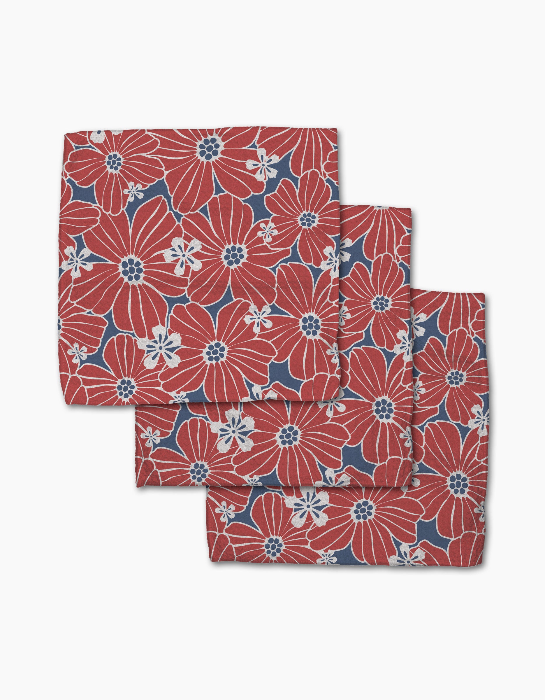 The Ashley Celena Botanical Blush set features three folded cloth napkins with bold red and white floral patterns on a dark blue background, neatly stacked for display against a crisp white backdrop.