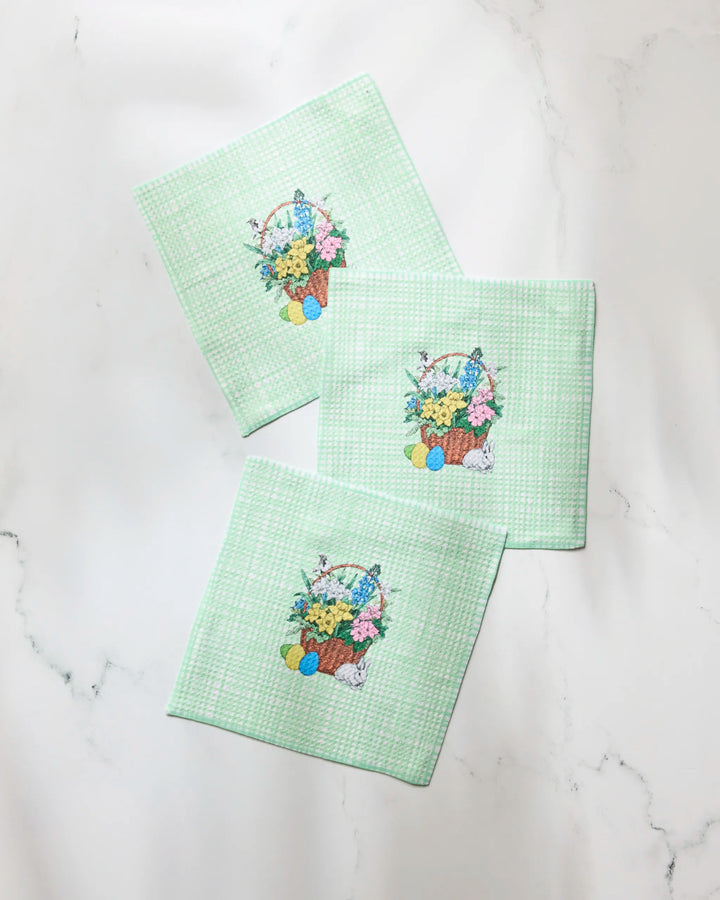 Three pale green Bunny Basket napkins from Geometry, made of recycled materials, display a pastel Easter basket, eggs, and bunny design and are set on white marble.
