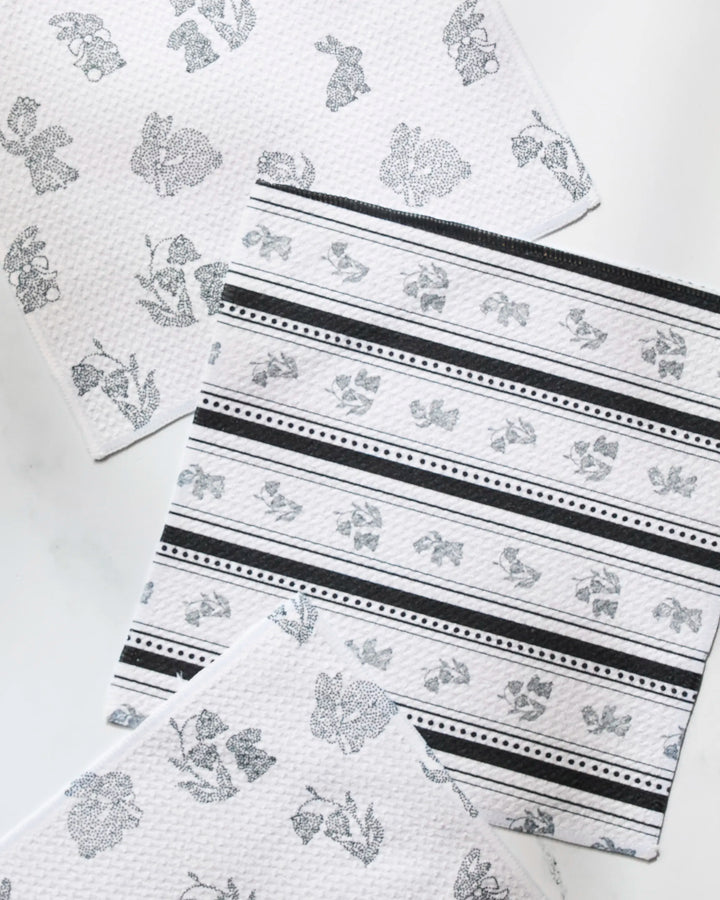 The Geometry Bunny Dots dishcloth set includes three white cloths with black stripes, florals, and leaf prints. Made from recycled materials, these stylish towels are also super-absorbent for top kitchen performance.