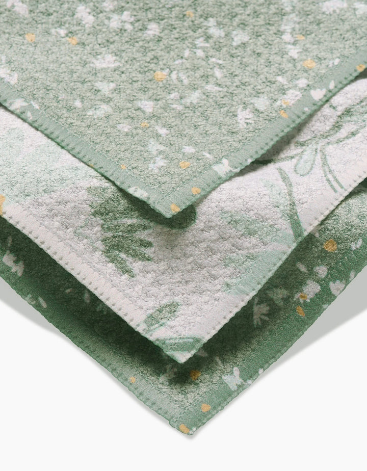 Three soft, green Bunny Tea Time towels from Second Nature Studio are stacked neatly. Made of absorbent Geoweave fabric, each towel features unique white and yellow floral patterns and different edge designs on each layer.