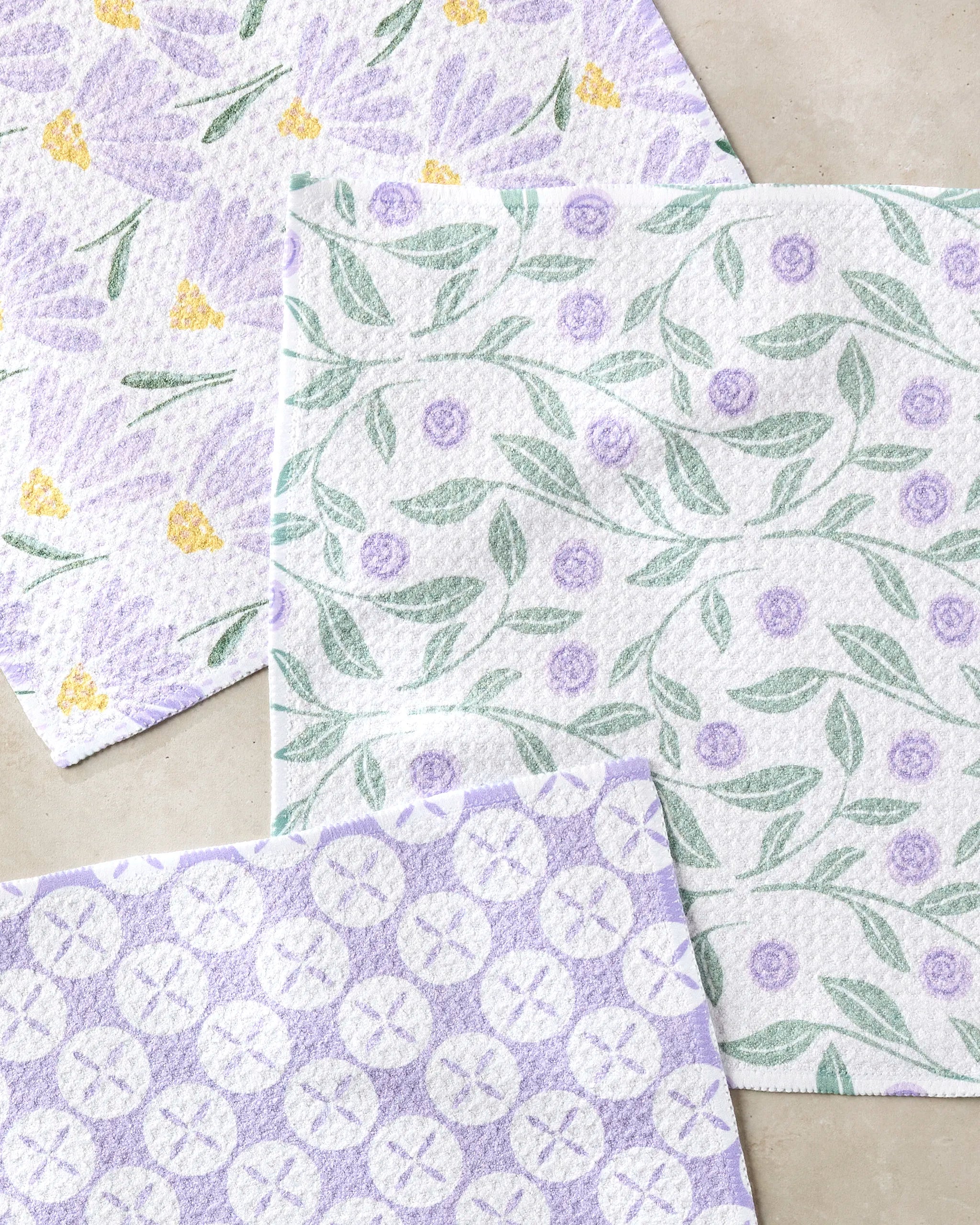 Three Button Vines and Daisies cleaning cloths by Hufton Studio, featuring pastel floral and circular patterns in purple, green, and yellow, are crafted from recycled materials for super-absorbent performance.