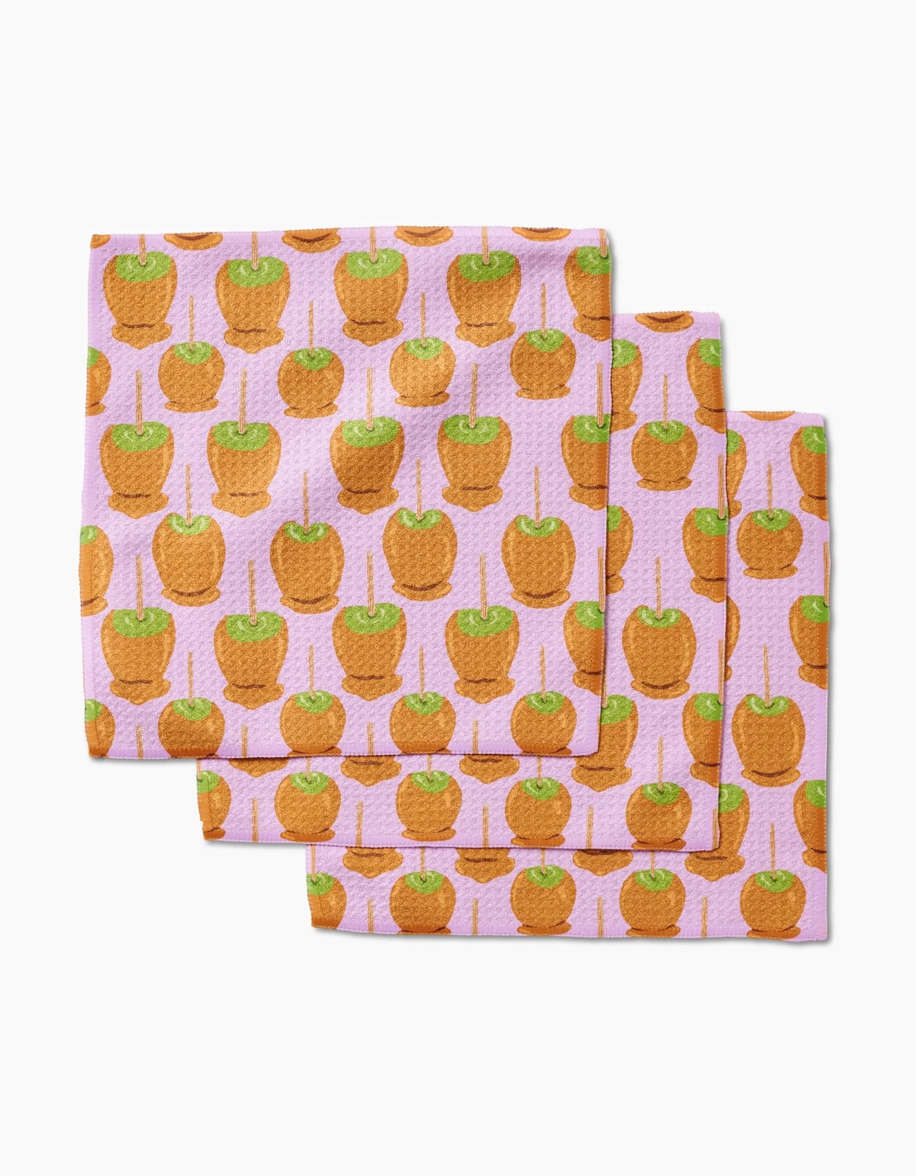 Set of three recycled napkins by Elisabeth Wing, featuring the Caramel Apple design—green caramel apples on sticks displayed on a light pink background.