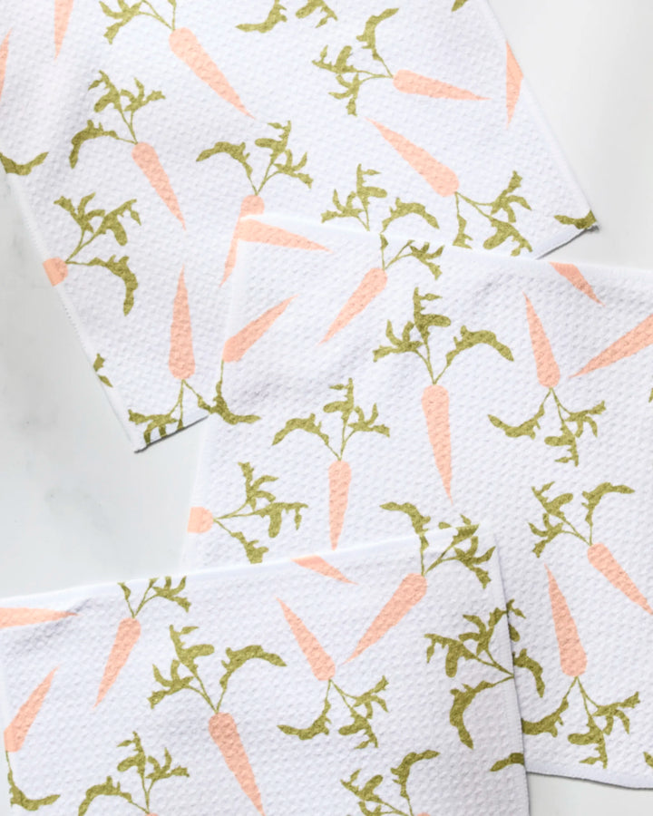 Geometry’s Carrot Toss super-absorbent dish towels feature a white background with overlapping light pink carrots and green tops, adding both charm and function to your kitchen.