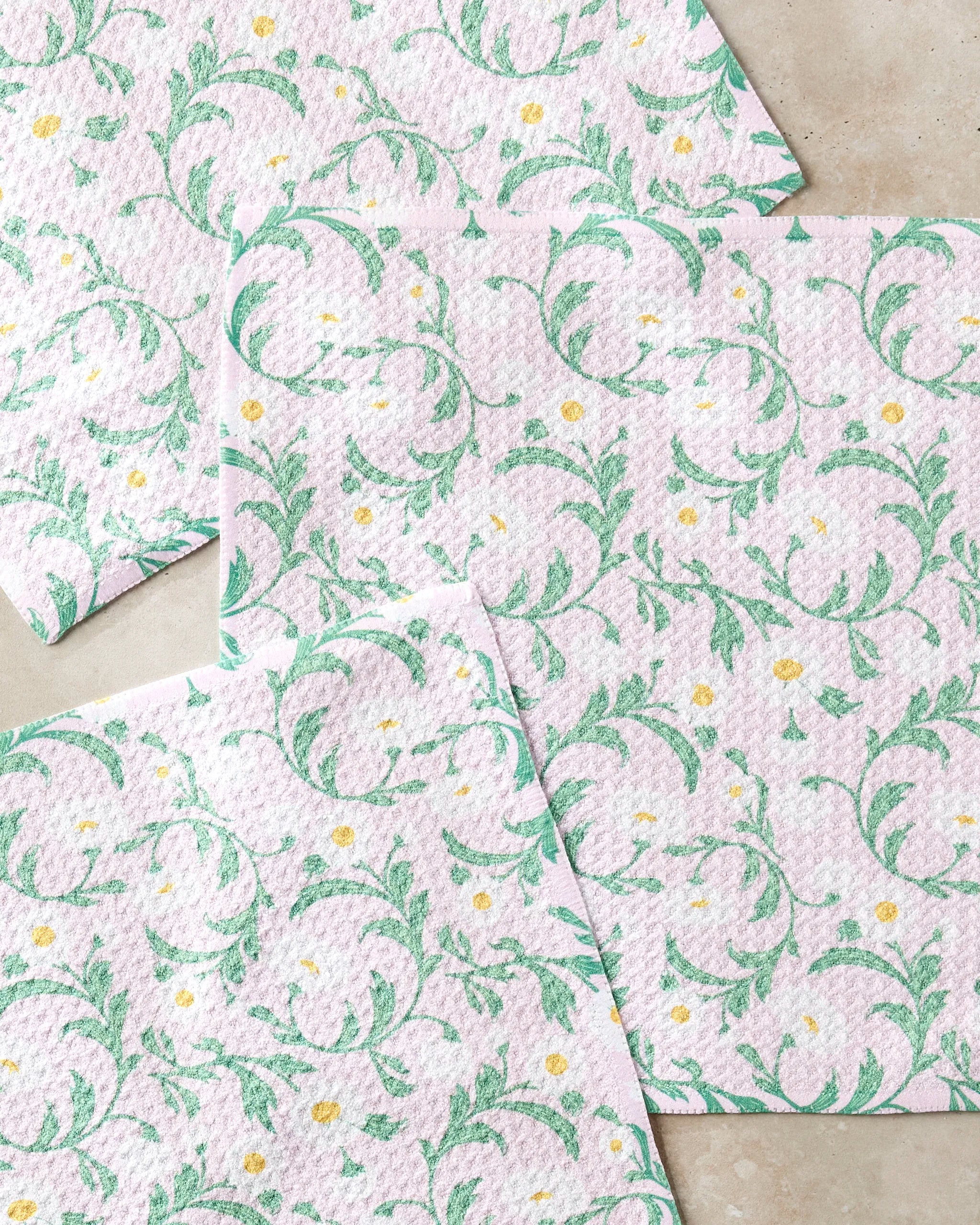 Four Chamomille paper napkins by Danelys Sidron feature a light purple background with green floral vines and small yellow-white flowers, blending eco-friendly charm inspired by recycled dishcloth trends.