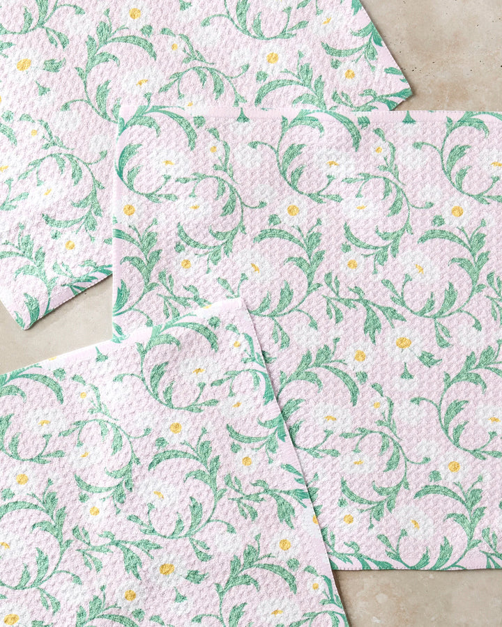 Four Chamomille paper napkins by Danelys Sidron feature a light purple background with green floral vines and small yellow-white flowers, blending eco-friendly charm inspired by recycled dishcloth trends.