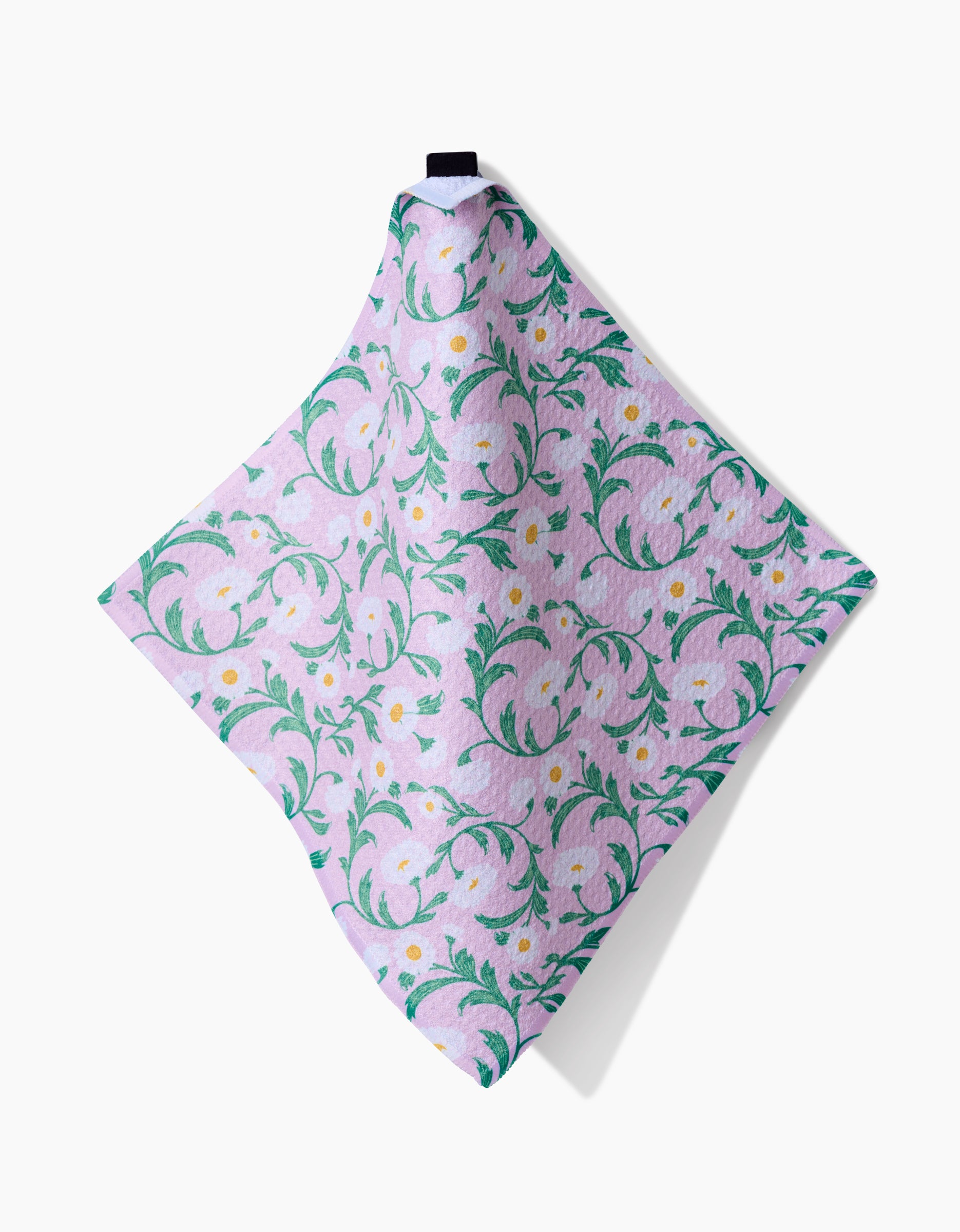 The Chamomille dishcloth by Danelys Sidron hangs diagonally on a white background, showcasing a soft, super-absorbent light purple design with green and yellow floral patterns and a small black loop at the top.