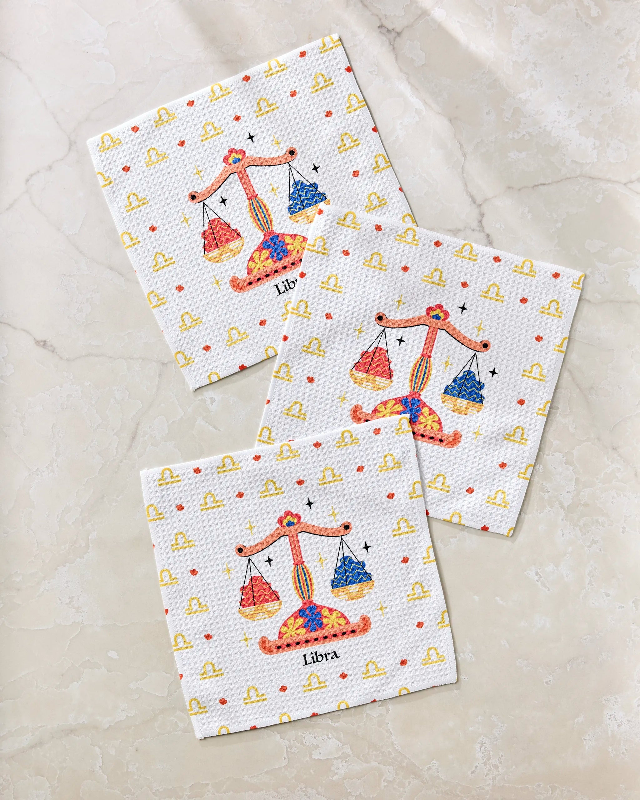 Three Charming Libra paper napkins by Heather Zhou, each with vibrant scales and yellow Libra symbols, are laid on marble. "Libra" appears below each design—a perfect eco-friendly match for your recycled materials dishcloth set.