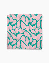 The Cheetah Haven dishcloth set by Jasmine Blooms Designs features folded pink cloths with a teal abstract, teardrop-like pattern, crafted from recycled materials and shown on a white background.