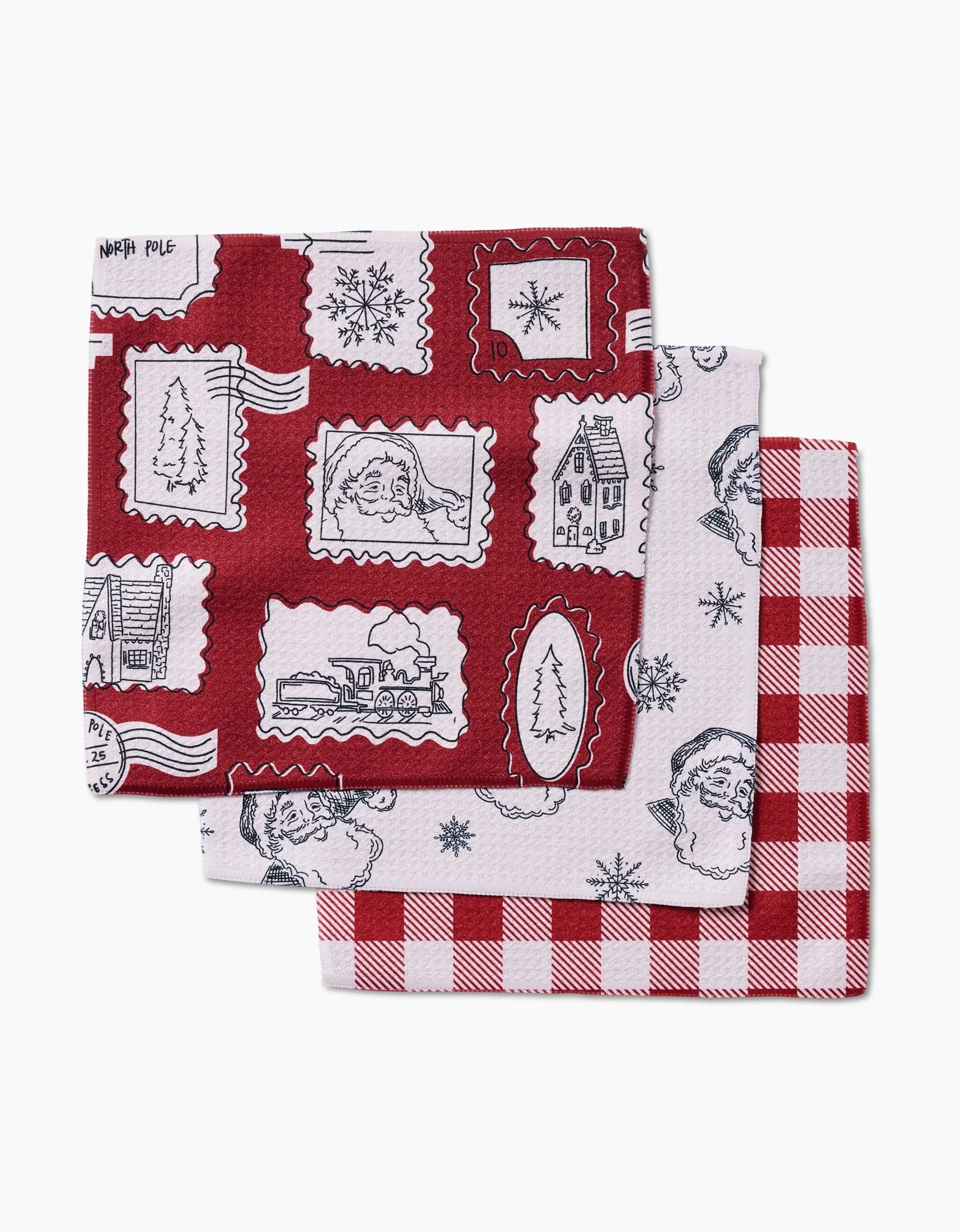 The Aubrey Fairchild Christmas Santa set includes three folded red and white dishcloths with festive Santa, tree, house, train, and snowflake patterns—perfect for the holidays and made from recycled materials.