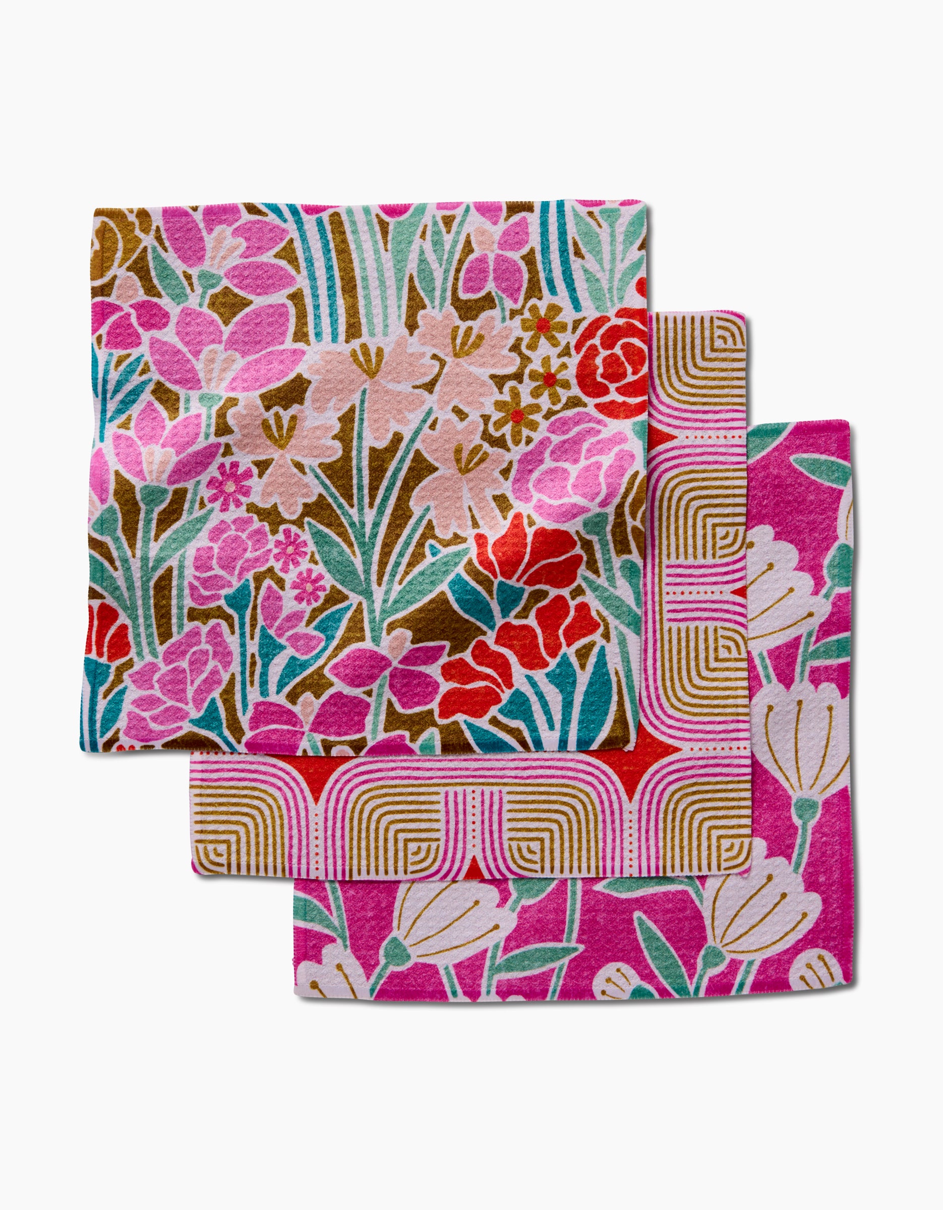 Clemmie, Donna, and Janae by Amy MacCready are three vibrant cloth napkins made from recycled materials with floral and geometric patterns in pink, red, green, and gold, shown stacked on a white background.