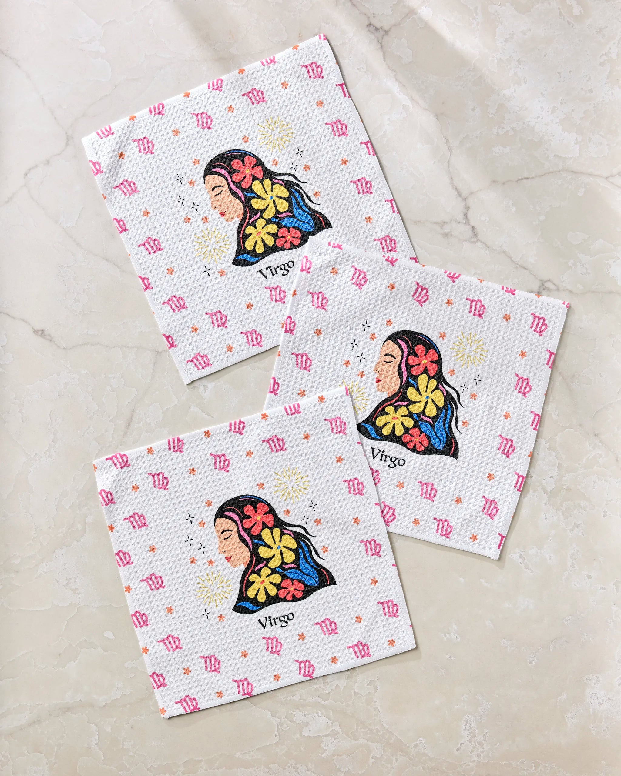 Three “Clever Virgo” paper napkins from Heather Zhou, made with recycled materials, feature illustrations of women with floral hair, the word "Virgo," and pink Virgo zodiac symbols on a marble surface.