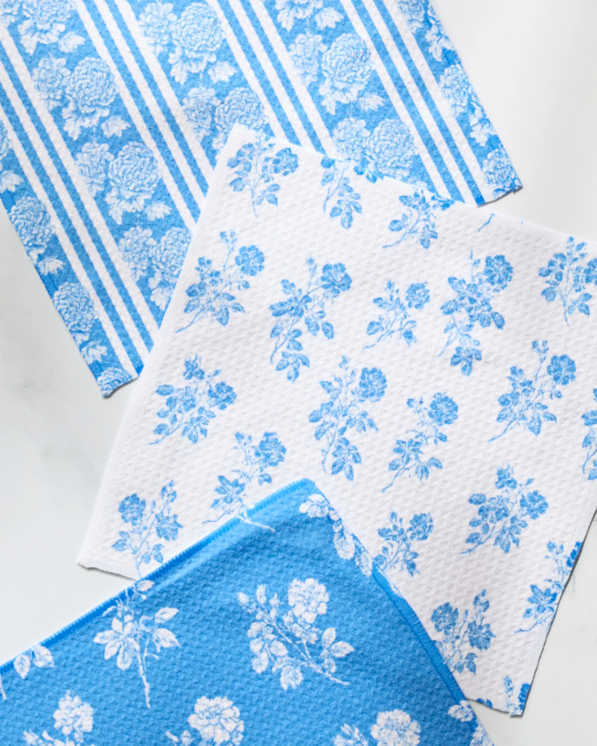 The Geometry Crete dishcloth set includes three recycled, fast-drying cloths in blue and white with floral and striped patterns—bringing style and function to your kitchen.