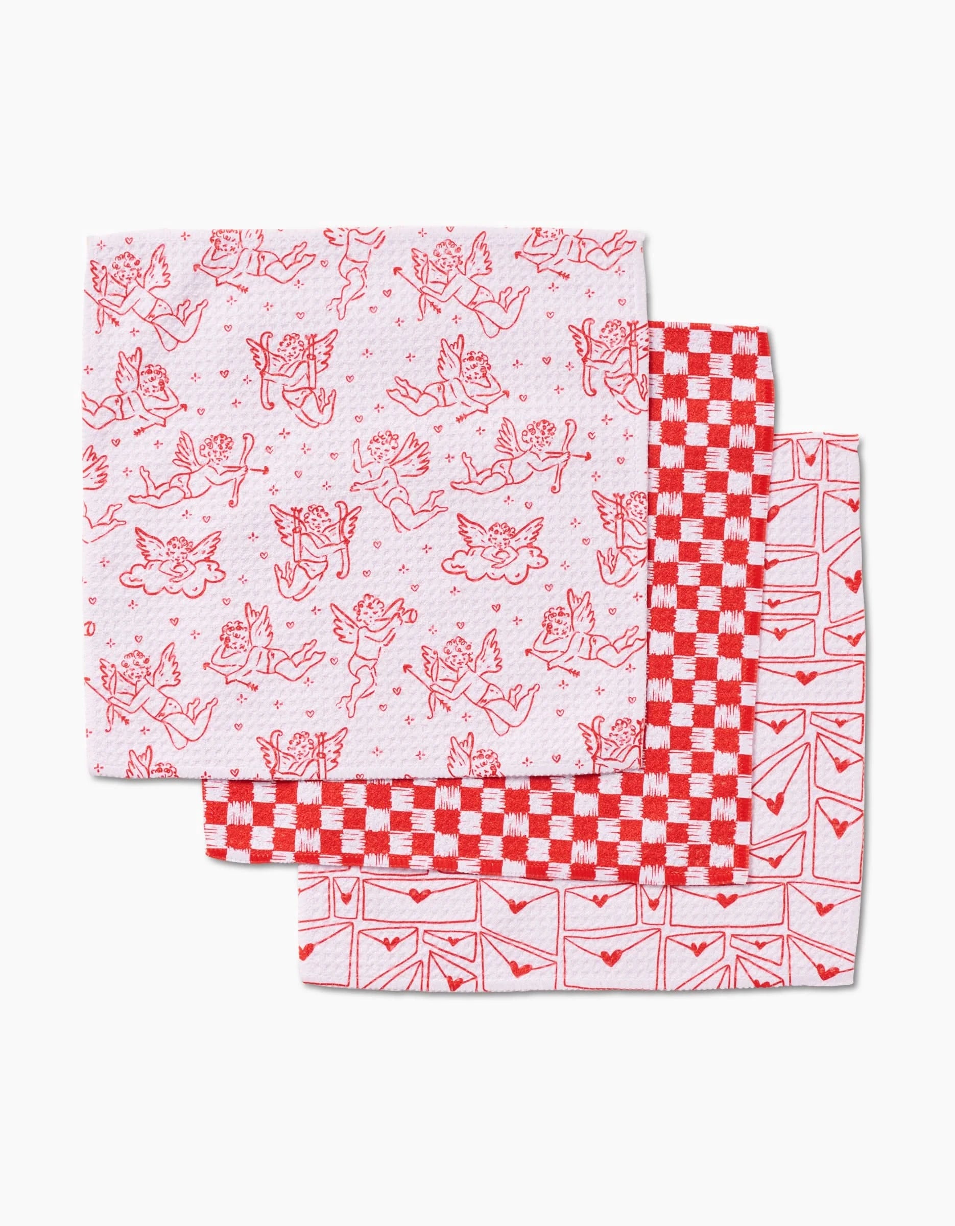 Kayla Ann’s Cupids My Valentine set includes three reusable dishcloths made from recycled materials, featuring playful red patterns: whimsical motifs, a red and white checkerboard, and a repeating love letter design.