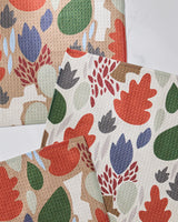 The Geometry Cut Paper Leaves set includes three super-absorbent, textured dishcloths featuring abstract botanical patterns in red, green, blue, and beige. Leaf and plant designs overlap on a light background.