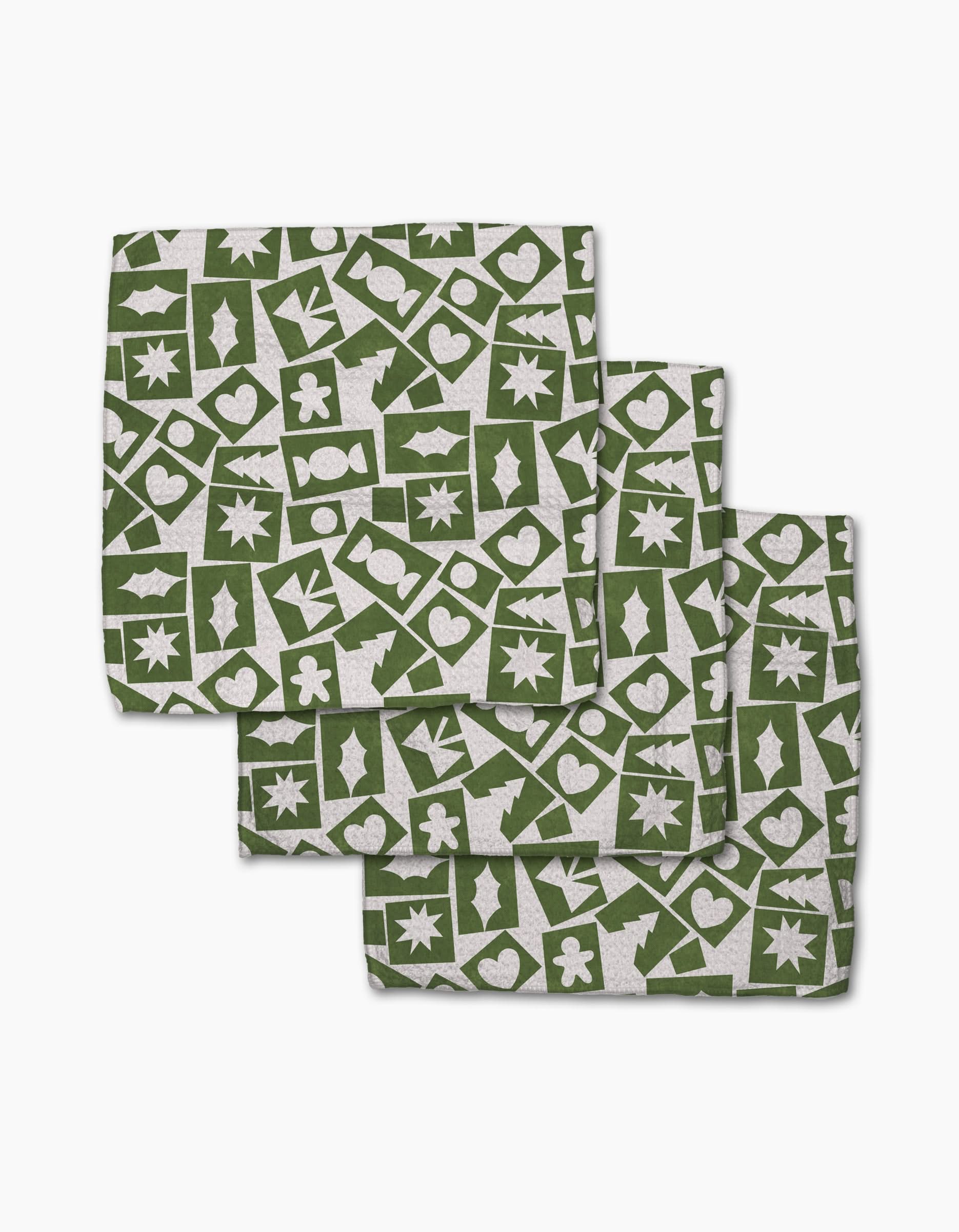 Three folded Cutout Christmas napkins by Claire Iglesias with a green and white holiday pattern—stars, trees, hearts, snowflakes, gingerbread—in a grid. Made from recycled materials, this festive set is eco-friendly.