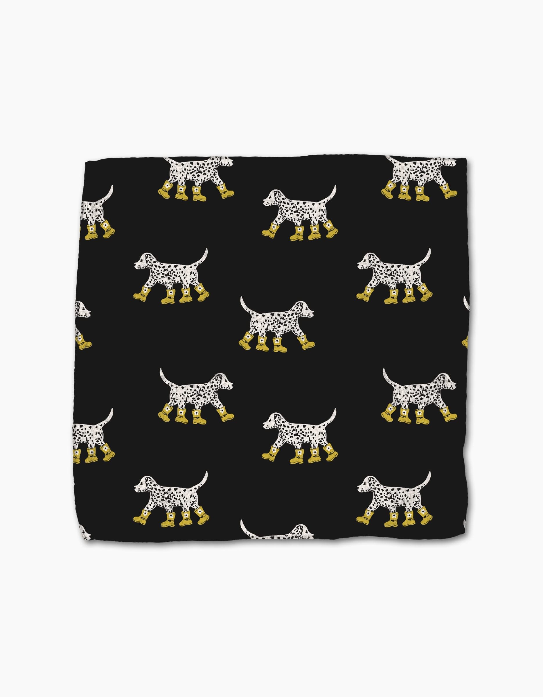 Geometry’s Dalmatian In Boots is a black, super-absorbent dishcloth made from recycled materials, featuring a pattern of white Dalmatian dogs in yellow boots facing both directions.