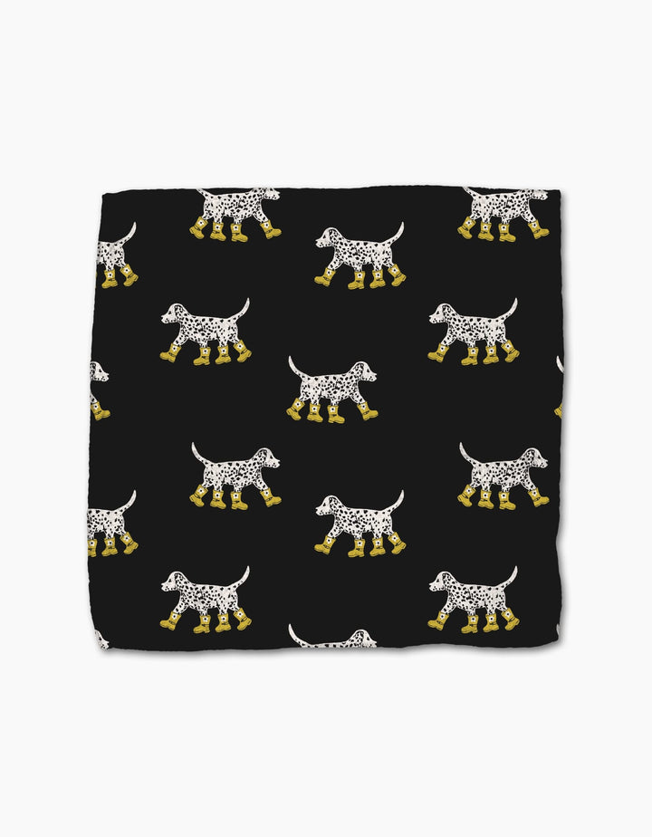 Geometry’s Dalmatian In Boots is a black, super-absorbent dishcloth made from recycled materials, featuring a pattern of white Dalmatian dogs in yellow boots facing both directions.