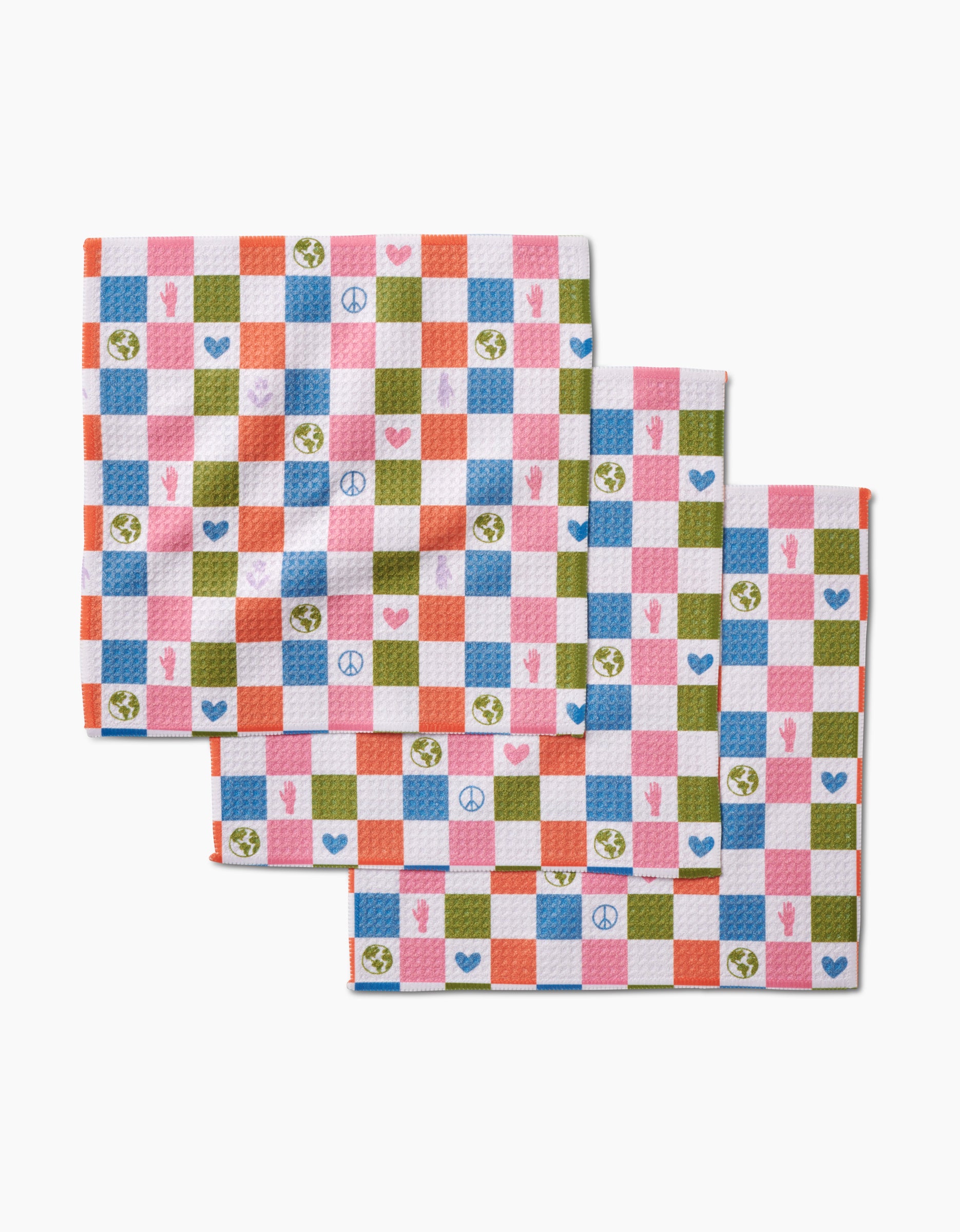 Kayla Ann’s Earth Day Checkers set includes three colorful Geoweave fabric dishcloths with a checkered pattern in pink, orange, blue, green, and white, adorned with peace signs, hearts, Earth symbols, and raised fists.