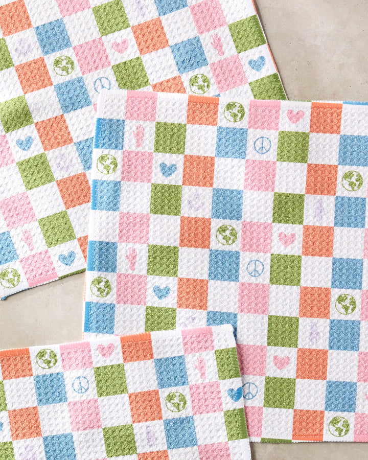 The Kayla Ann Earth Day Checkers kitchen towels feature a colorful pink, green, orange, and blue checkered pattern with heart, peace sign, Earth globe, and hand icons. This vibrant dishcloth set is displayed on a light surface.