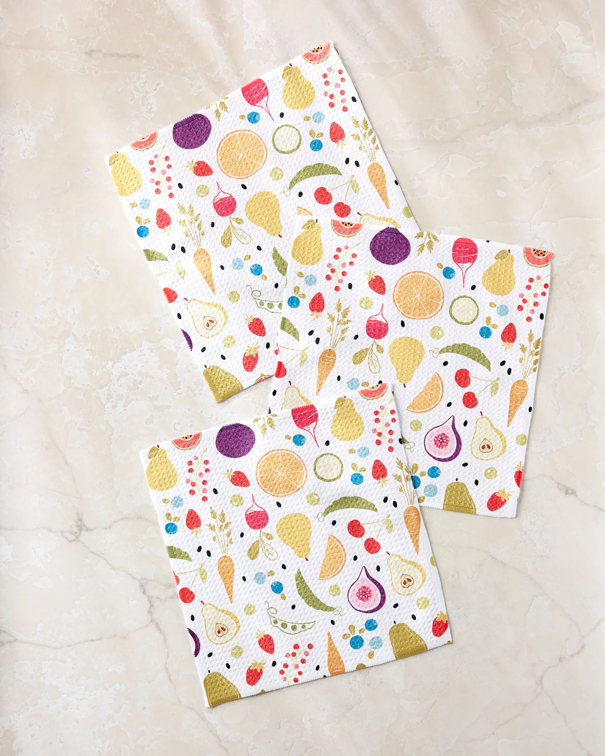 The Sara Mari Farmers Market set includes three recycled napkins with playful fruit and ice cream cone patterns—pears, strawberries, cherries, watermelon—brightly displayed on a light marble surface.