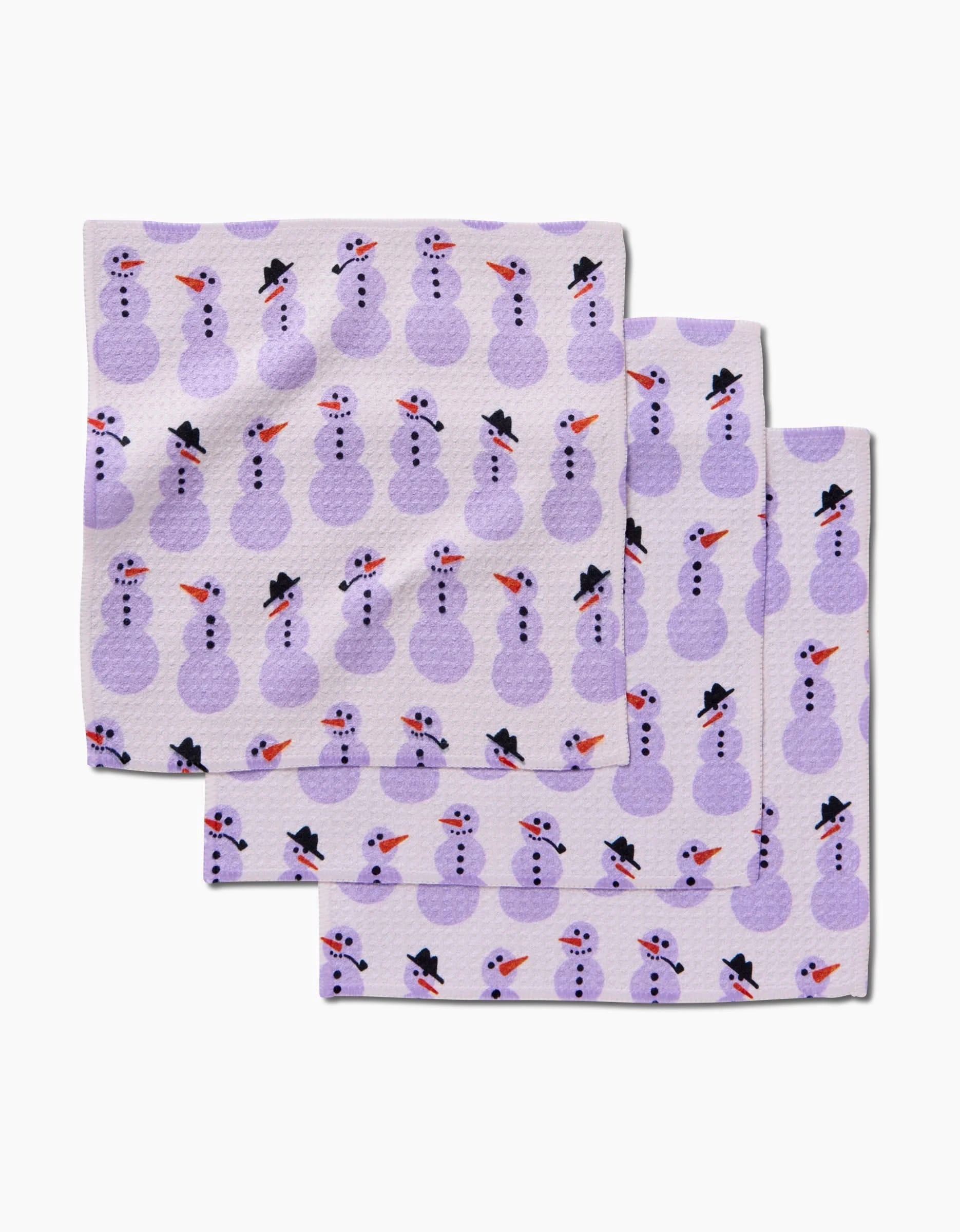 The Amy MacCready Felicity Purple set includes three light kitchen tea towels with overlapping purple snowmen wearing black hats, orange carrot noses, and red scarves on a white background.