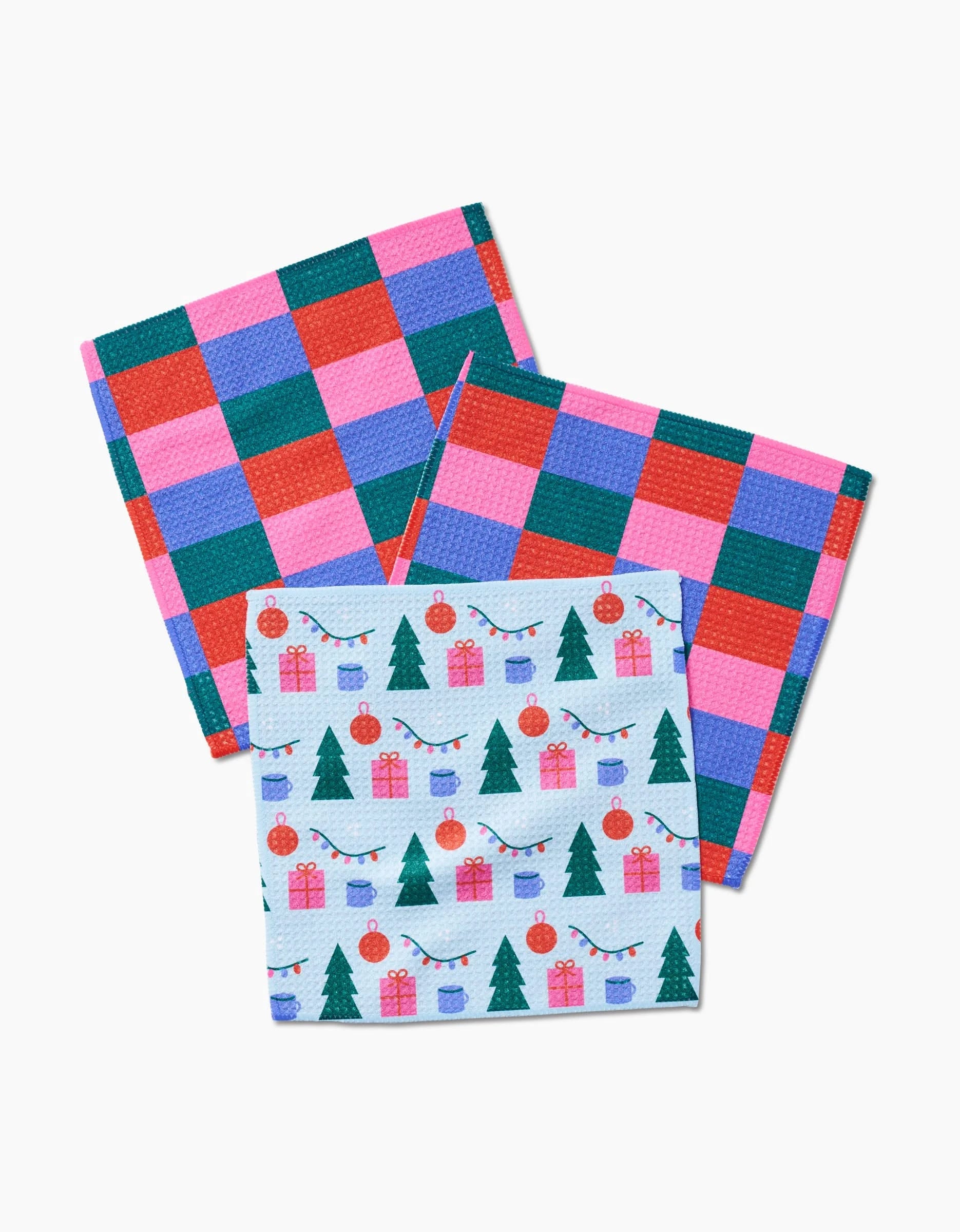 Three Festive Doodles dishcloths by Laura Supnik are pictured: two have colorful checkered patterns, and the third displays Christmas trees, ornaments, and presents. All are crafted from super-absorbent recycled materials.