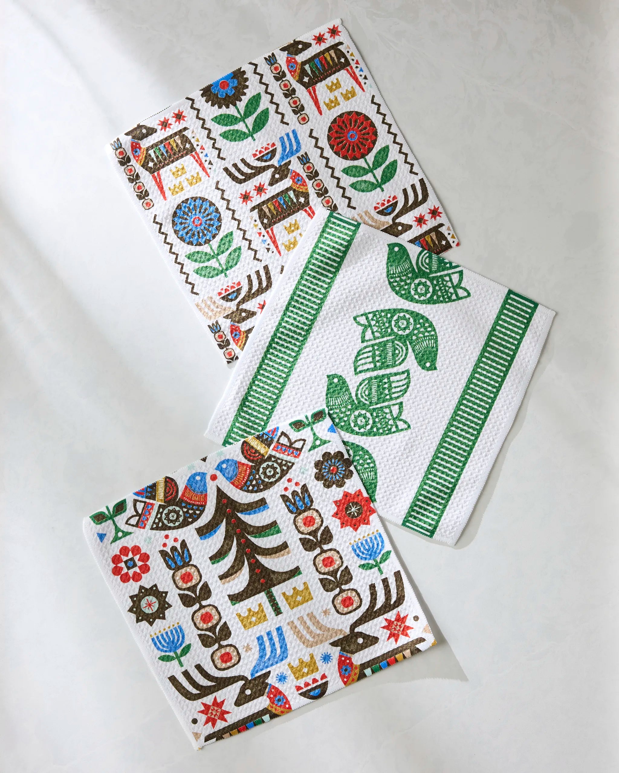 The Festive Folk dishcloth set by Geometry features super-absorbent towels with colorful, folk-inspired patterns made from recycled materials—adding a unique touch to your kitchen decor.