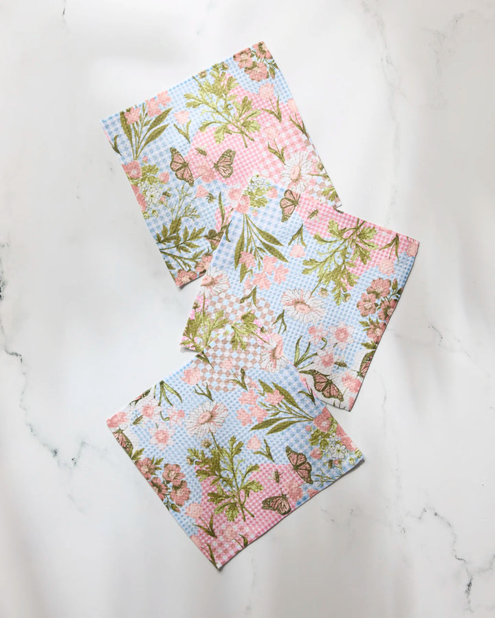 Three rectangular Geometry "Floral Collage" recycled kitchen towels, featuring pink, green, and blue pastel floral and butterfly patterns, are displayed on a white marble surface.