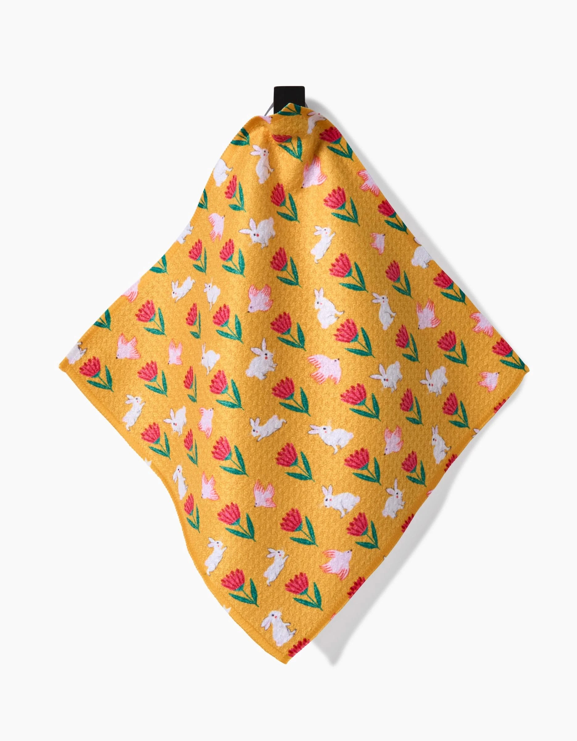 Floral Easter Parade by Ceyda Alasar is a yellow cloth made from recycled materials, featuring white bunnies and pink tulips with green leaves. It hangs from a black loop against a white background.