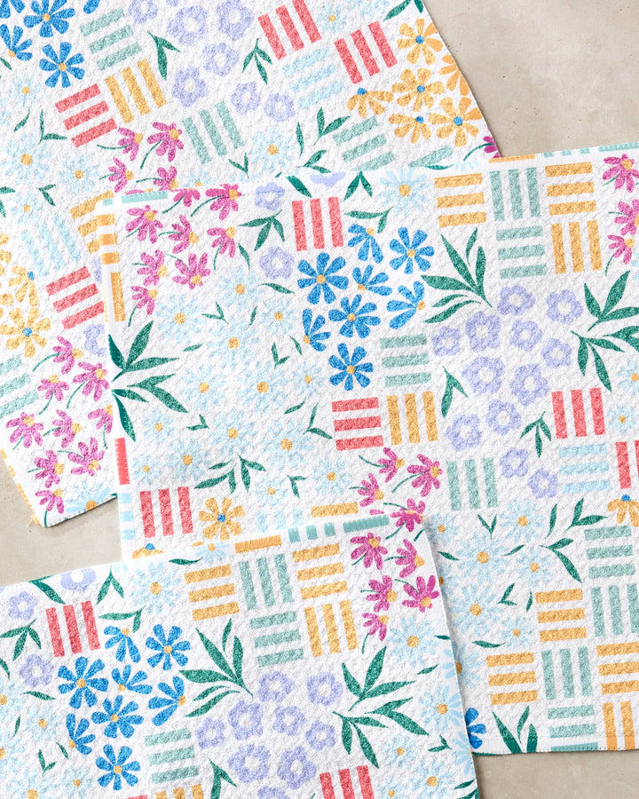 Floral Garden paper towels by Charlie Rowan Designs, made from recycled materials, feature textured surfaces with pink, blue, yellow, and green floral and geometric patterns overlapping on a light beige background.