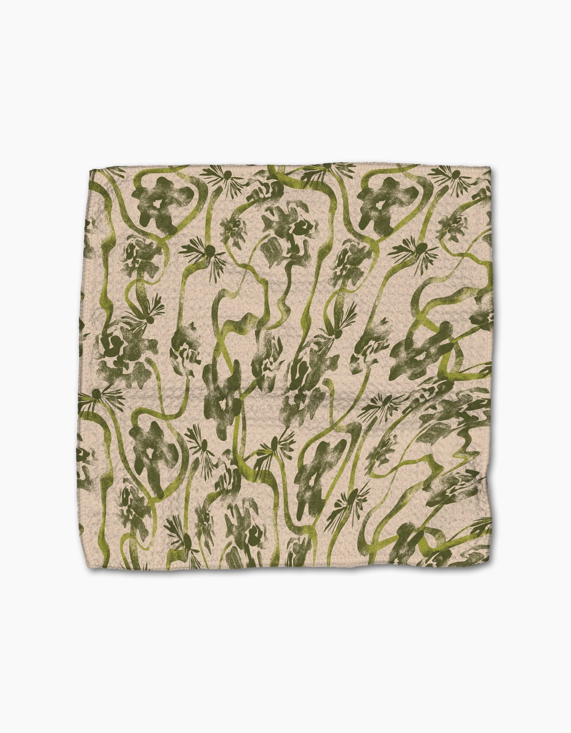 Geometry’s “Floral Swirls Green” dishcloth is square, beige, and made from recycled materials, featuring an abstract green jungle pattern with vines, leaves, and playful monkeys.