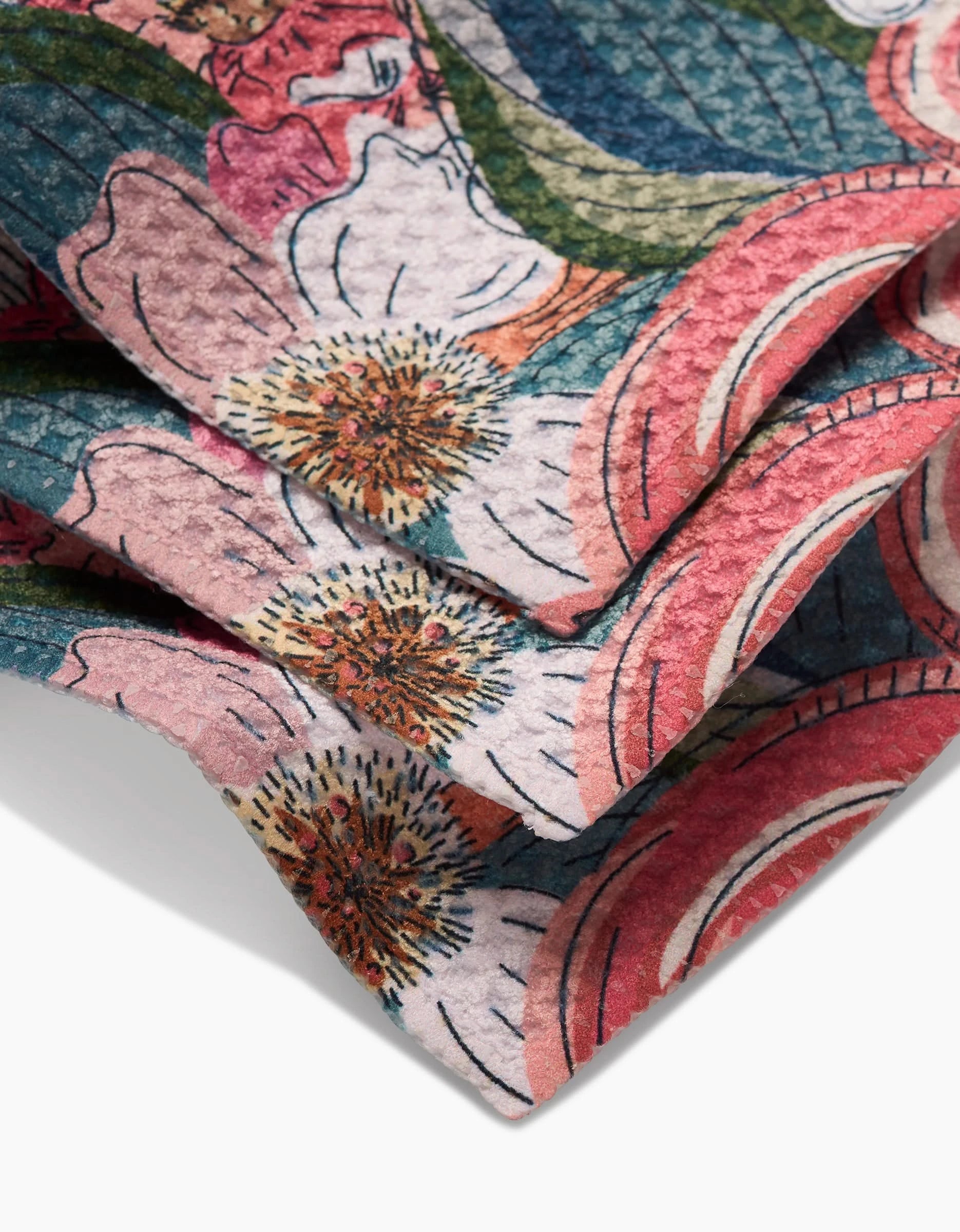 A close-up of the Flower Explosion Geoweave dishcloth by Second Nature Studio, showcasing its intricate pink, white, and red floral pattern with green leaves on textured fabric, neatly folded with visible creases.