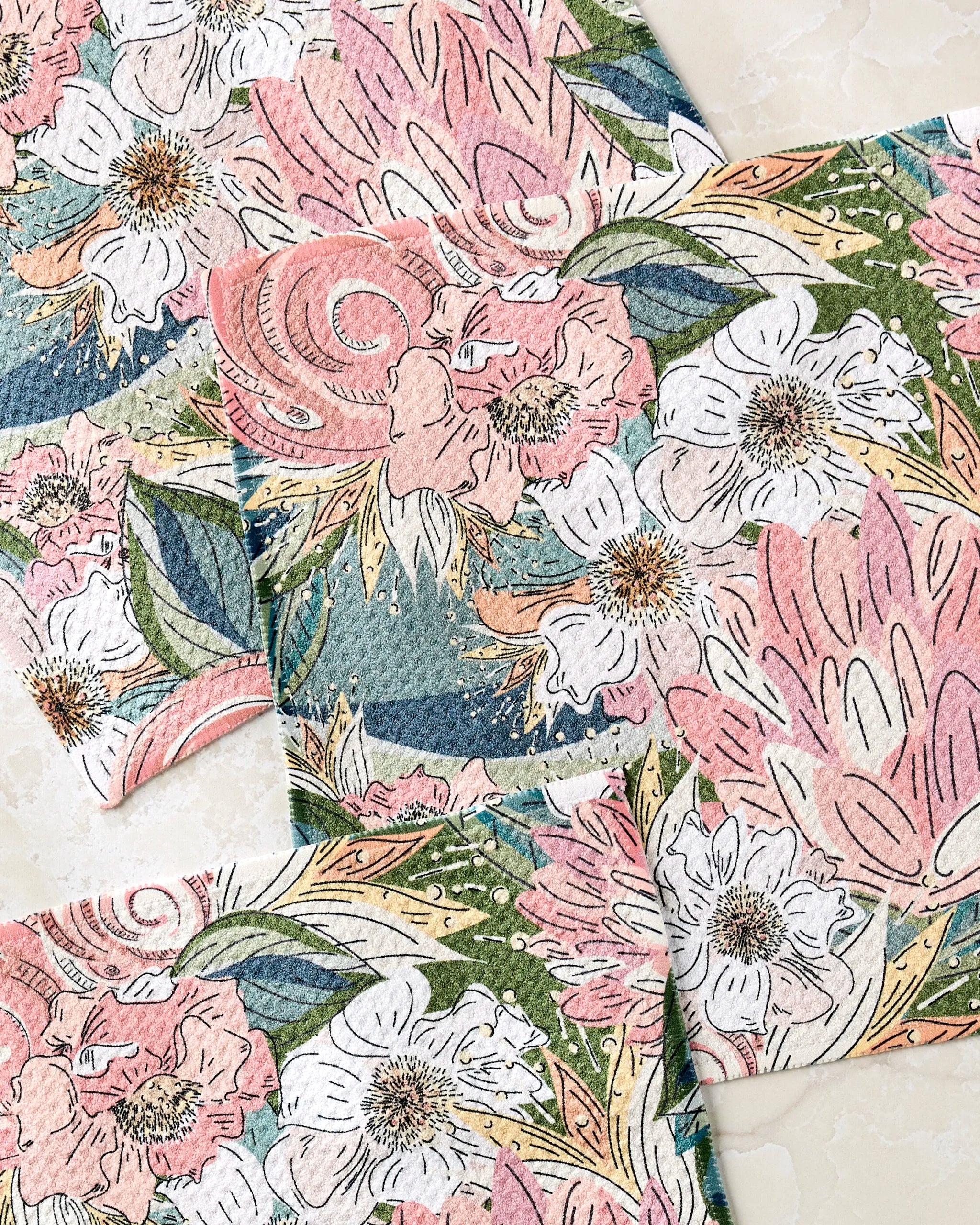 The Second Nature Studio Flower Explosion dishcloth set includes three super-absorbent towels with pink, white, and green floral patterns, made from recycled materials for an eco-friendly and artistic kitchen touch.