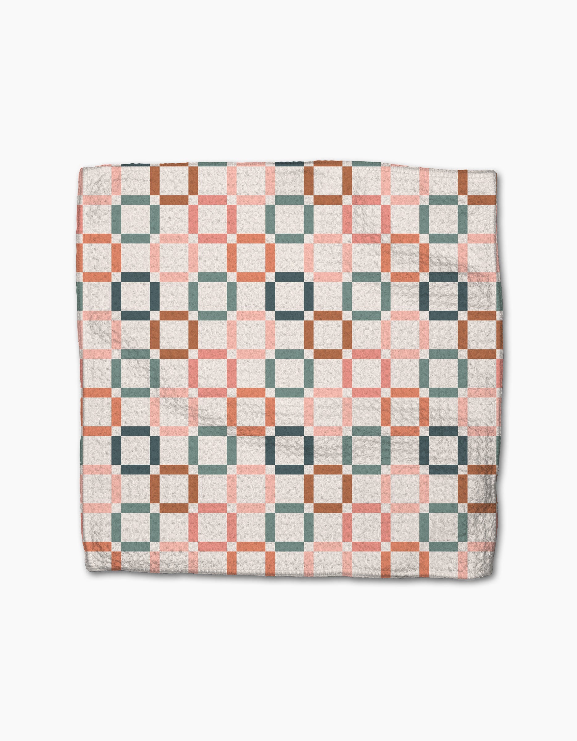 The Flower Patch quilt by Charlie Rowan Designs features interlocking pink, green, brown, and white squares in a geometric pattern on eco-friendly Geoweave fabric, displayed folded on a white background.