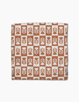 The Flower Patch dishcloth set by Charlie Rowan Designs features eco-friendly Geoweave fabric with a grid of brown and white squares, each adorned with abstract leaf or flower motifs—perfect for any kitchen.
