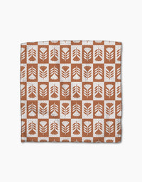 The Flower Patch dishcloth set by Charlie Rowan Designs features eco-friendly Geoweave fabric with a grid of brown and white squares, each adorned with abstract leaf or flower motifs—perfect for any kitchen.