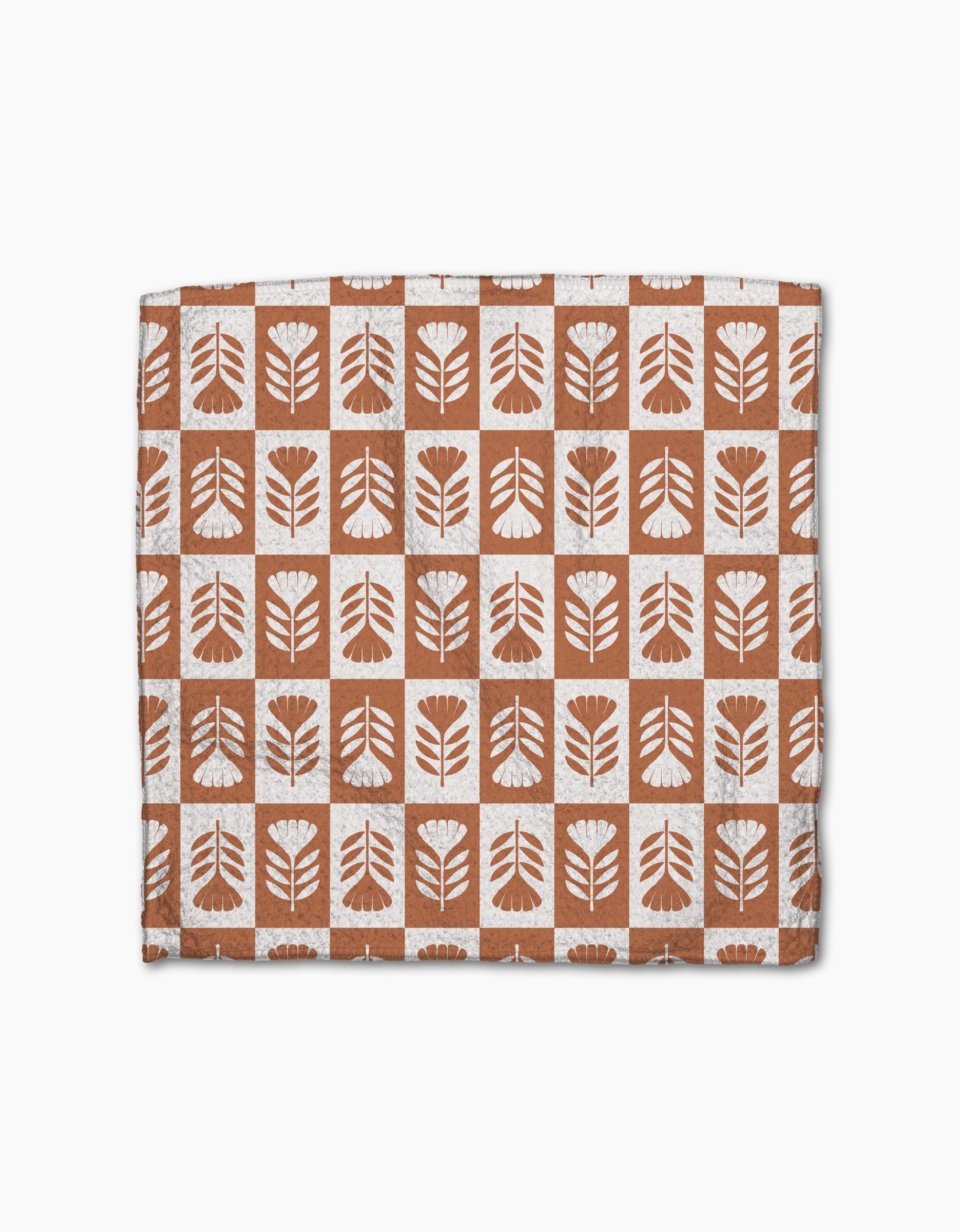The Flower Patch dishcloth set by Charlie Rowan Designs features eco-friendly Geoweave fabric with a grid of brown and white squares, each adorned with abstract leaf or flower motifs—perfect for any kitchen.
