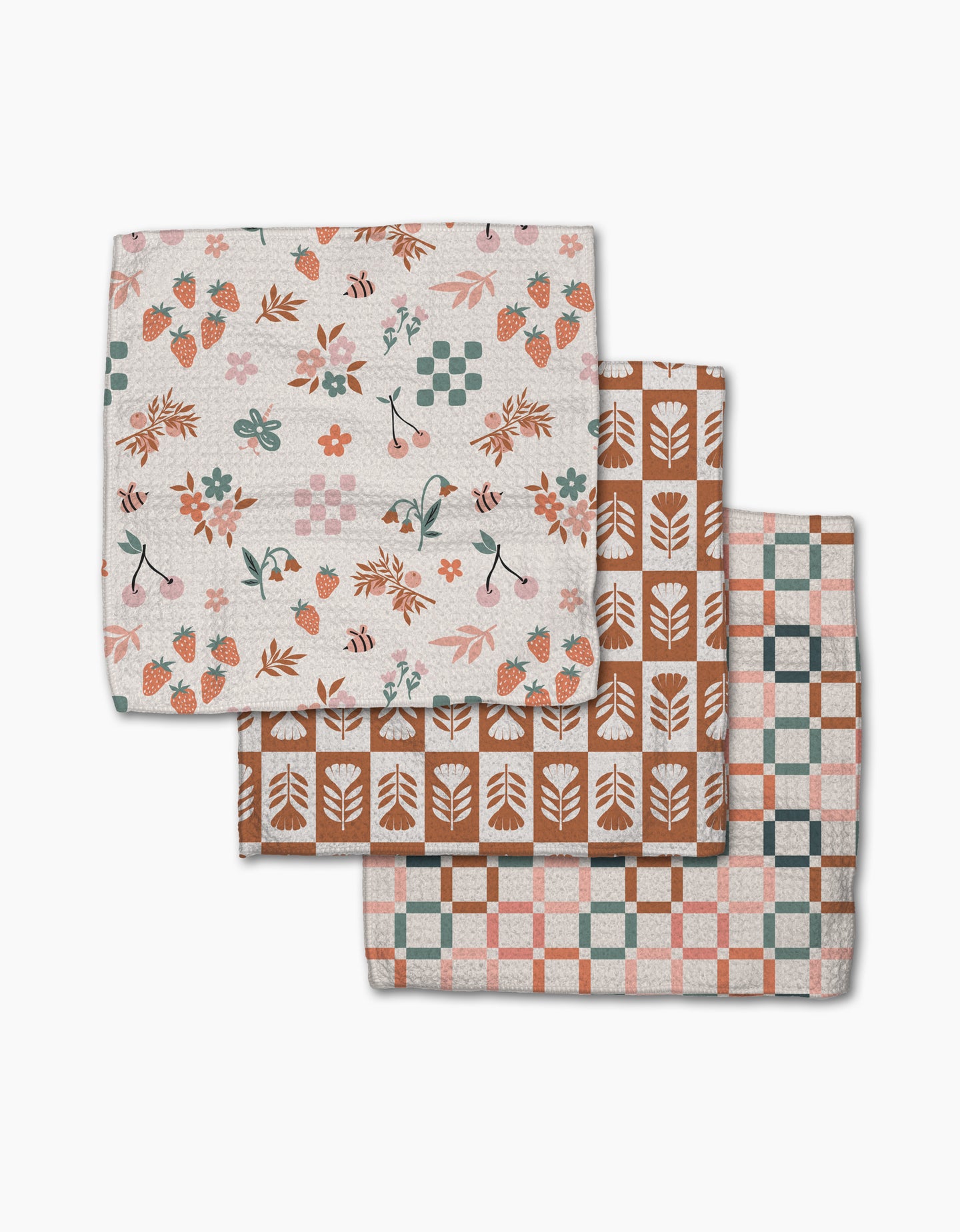 The Flower Patch Dishcloth Set by Charlie Rowan Designs features three eco-friendly Geoweave cloths, each with a unique pattern: strawberries and flowers, geometric leaves, and pink-teal-brown checks—all on a white background.