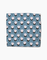 The Forest Findings blanket by Anette Heiberg is blue with a repeating tulip-inspired flower pattern in white and black, featuring green stems and leaves, crafted from recycled materials.