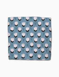 The Forest Findings blanket by Anette Heiberg is blue with a repeating tulip-inspired flower pattern in white and black, featuring green stems and leaves, crafted from recycled materials.