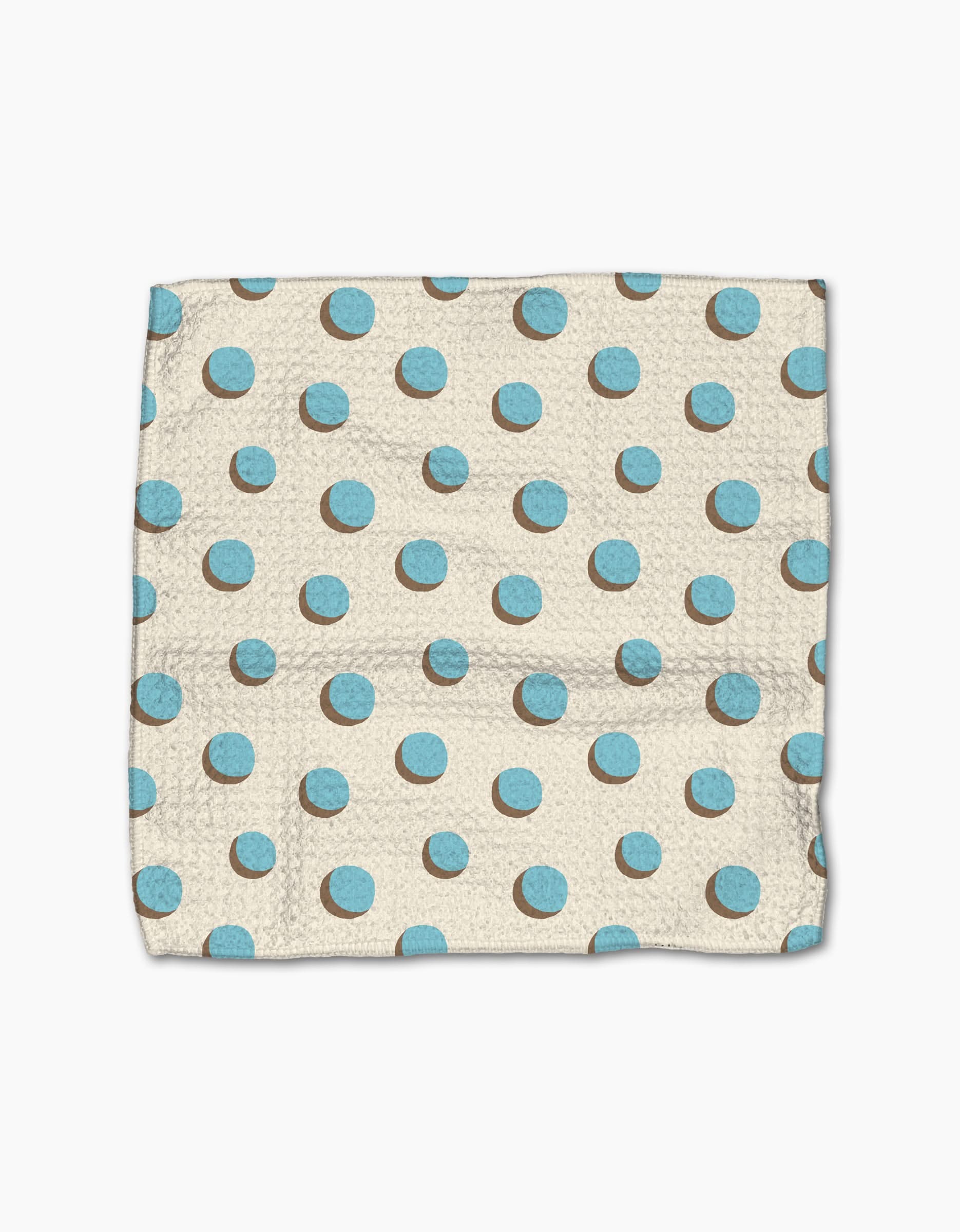 The Geometry Four In A Row Dot dishcloth, featuring a beige base with blue and brown polka dots and made from super-absorbent Geoweave fabric, is laid flat on a white background.
