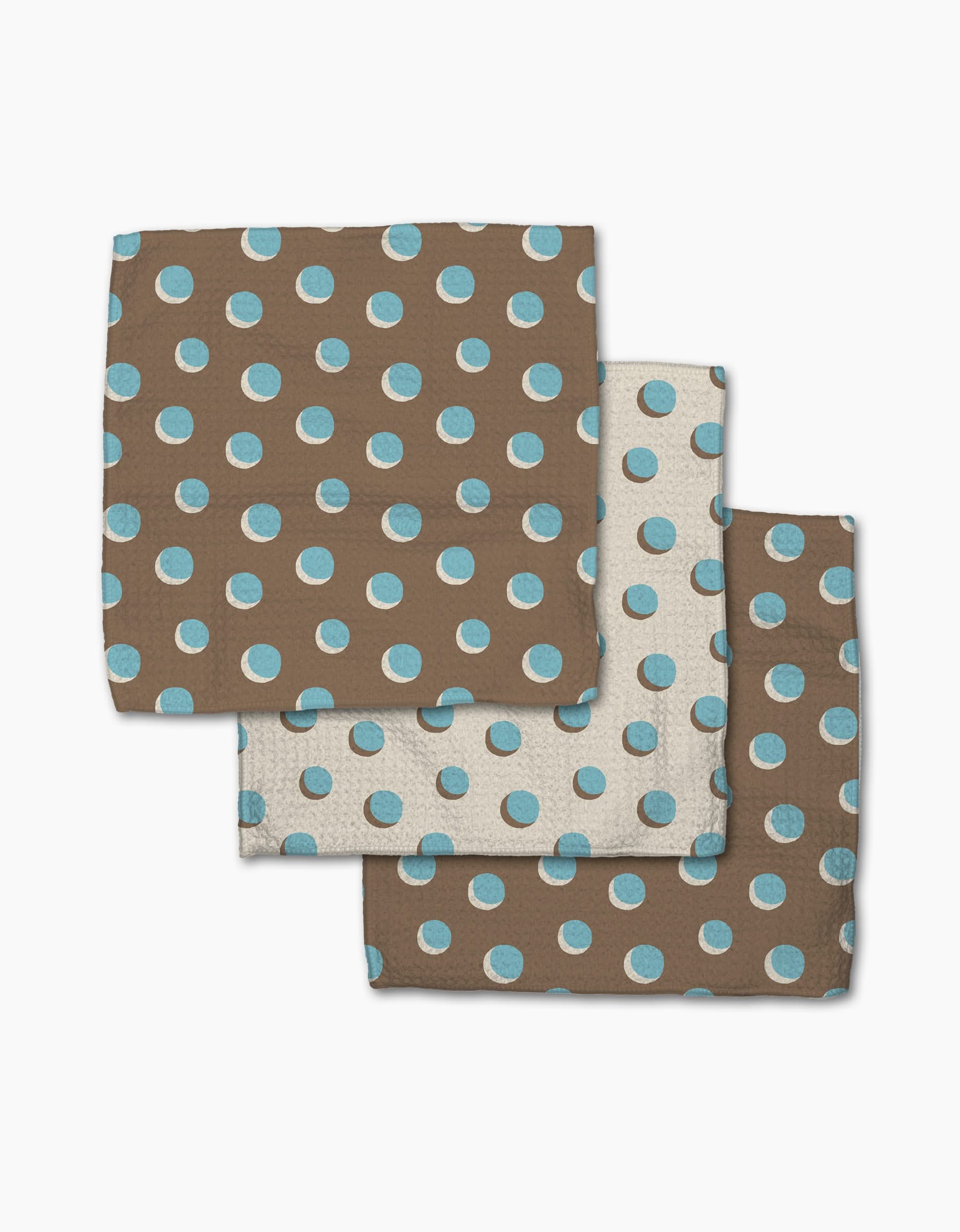 Geometry’s Four In A Row Dot set includes three Geoweave cloth napkins featuring a brown background with light blue dots, plus a white napkin with blue dots—stylish and super-absorbent for any kitchen.